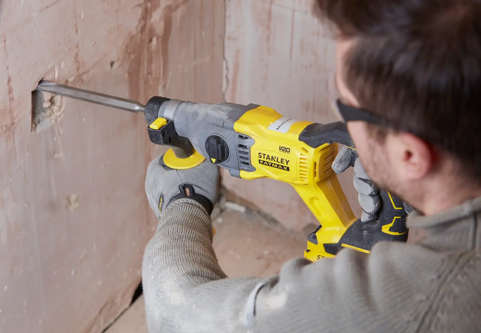 Photo of STANLEY SFMCH900M12 rotary hammer used on plaster wall in construction setting.