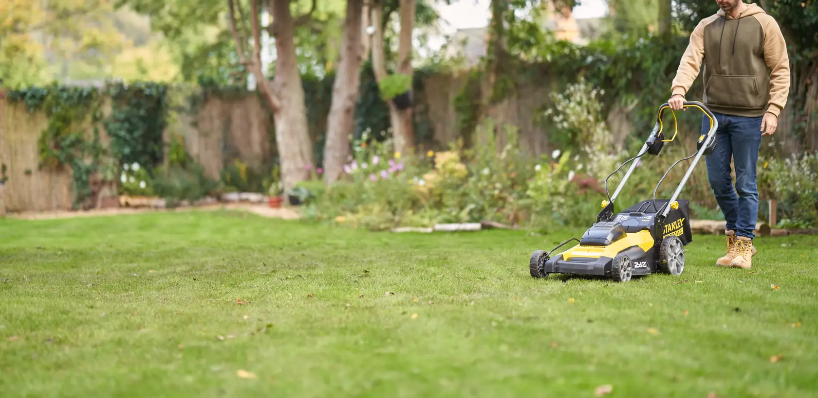 Photo of STANLEY SFMCMWS251B lawn mower in use on garden lawn.