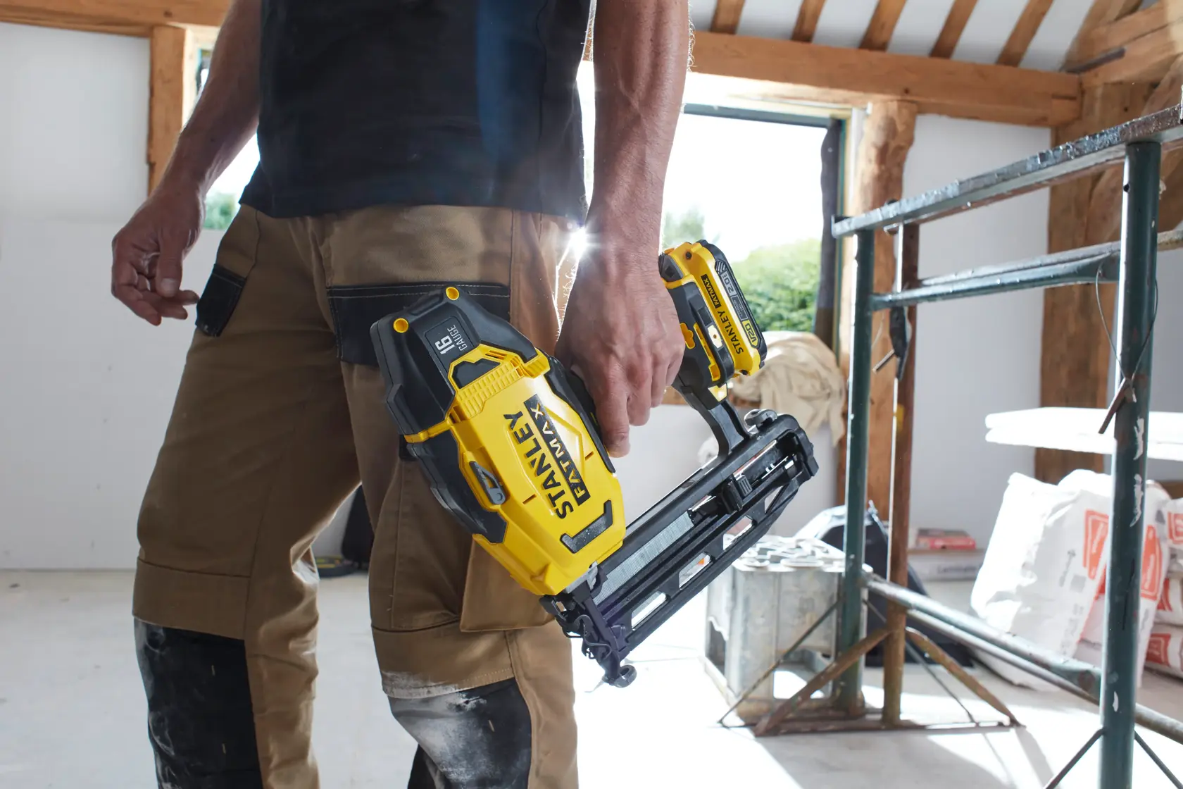 STANLEY SFMCN616D2K cordless nailer held by person in work pants at construction site.
