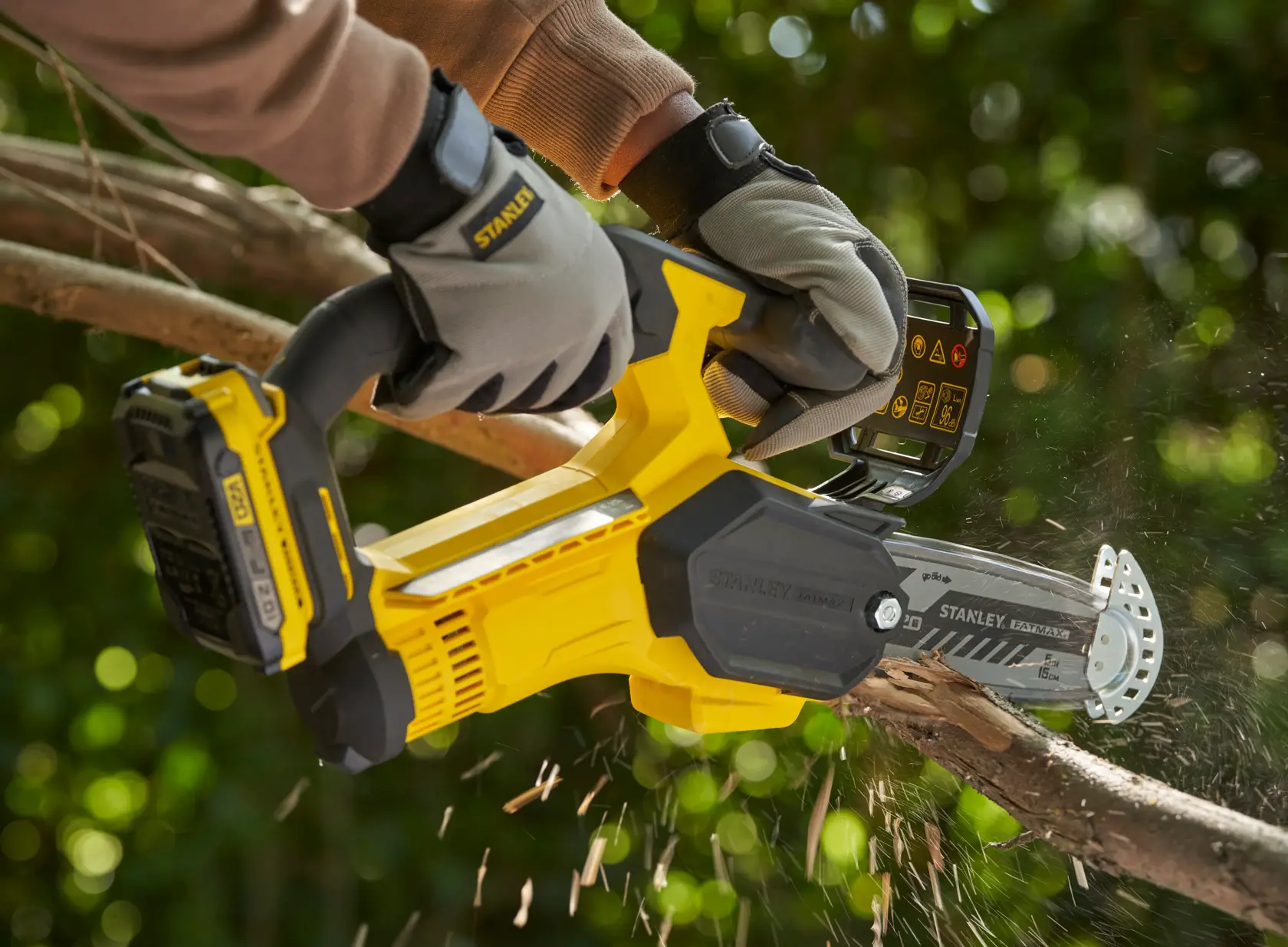 STANLEY SFMCPS415D1 cordless pruning saw cutting tree branch outdoors, close-up action view.