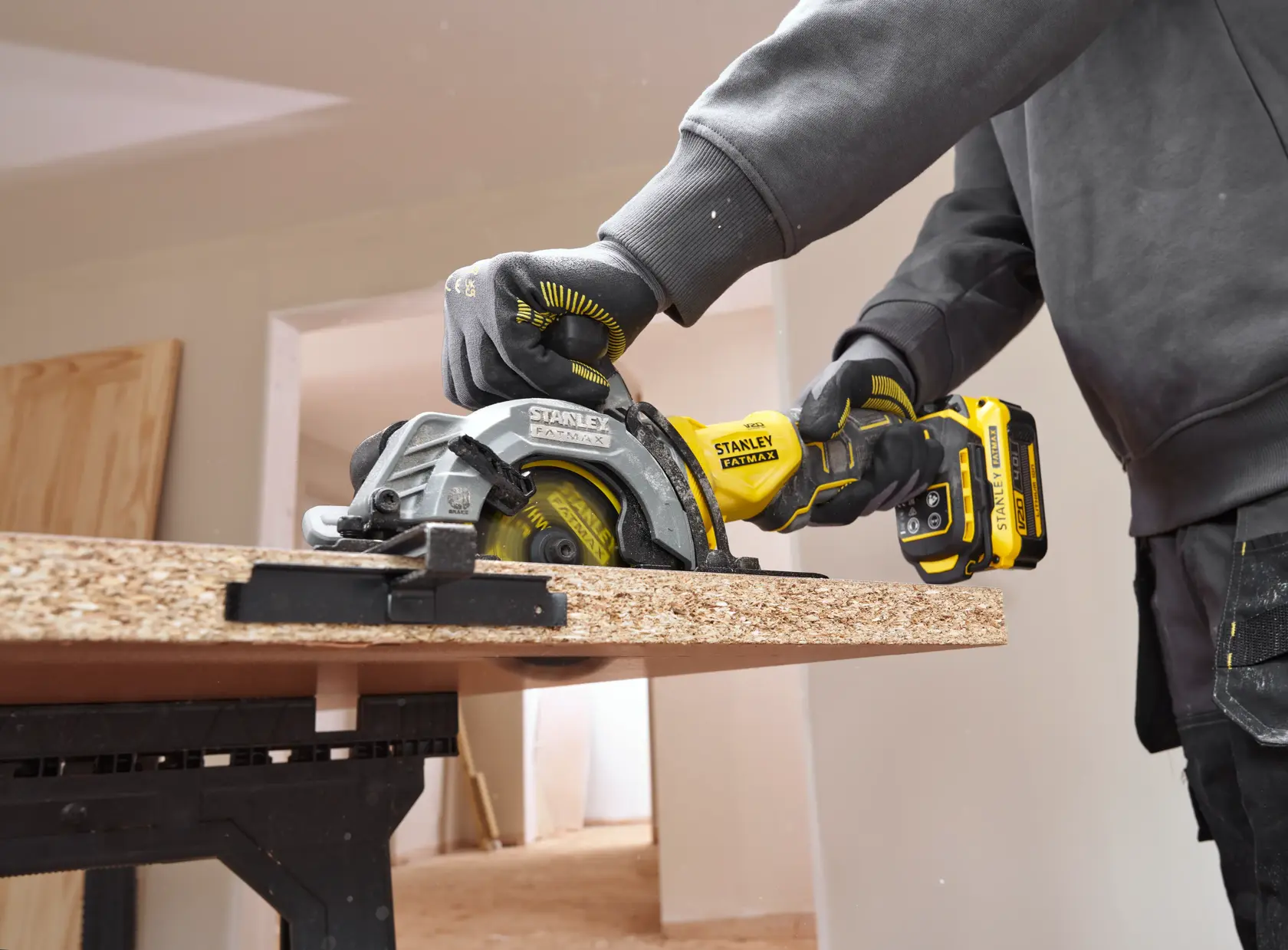 STANLEY SFMCS515B cordless circular saw in use cutting particle board, close-up of tool and hands.