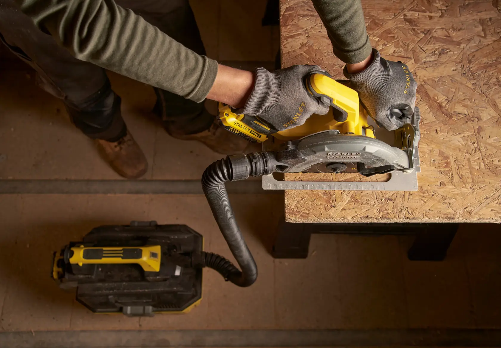 STANLEY SFMCS550M2K circular saw with dust extraction in use on wood panel, top view photography.
