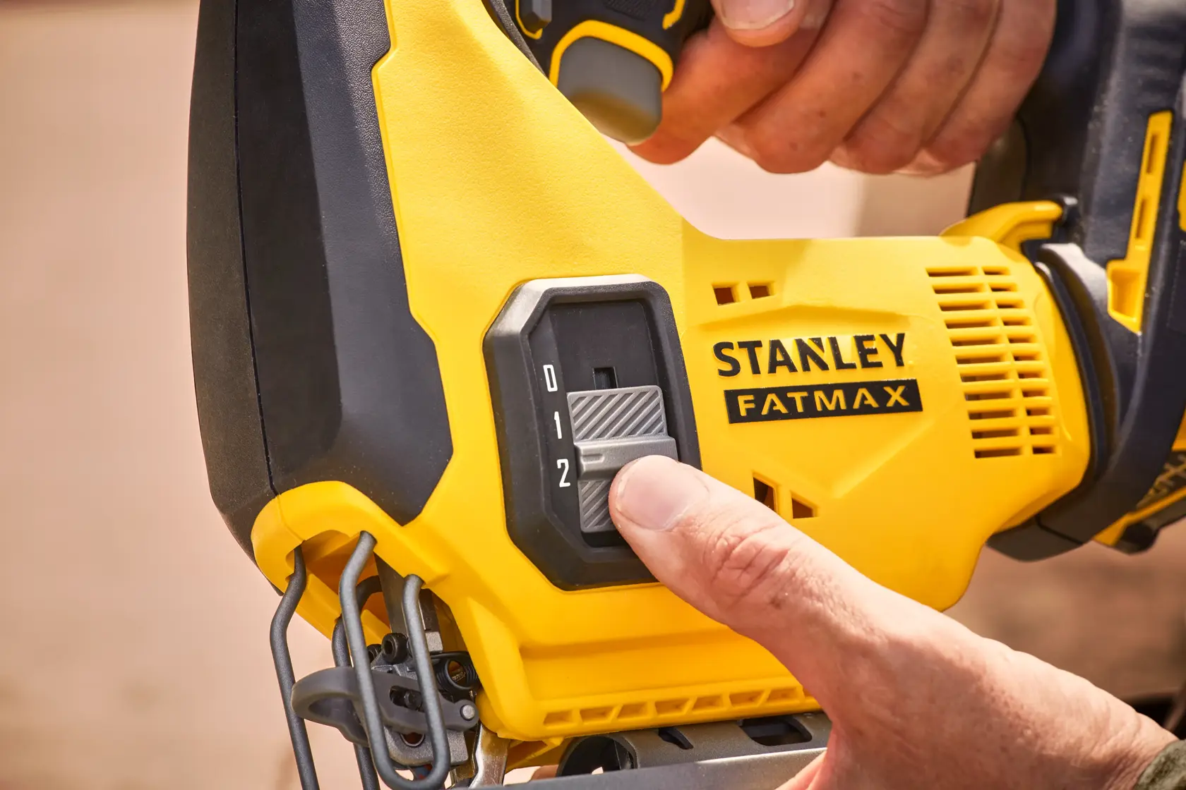 Photo of STANLEY SFMCS600M2K jigsaw speed control switch being adjusted, yellow and black tool close-up.