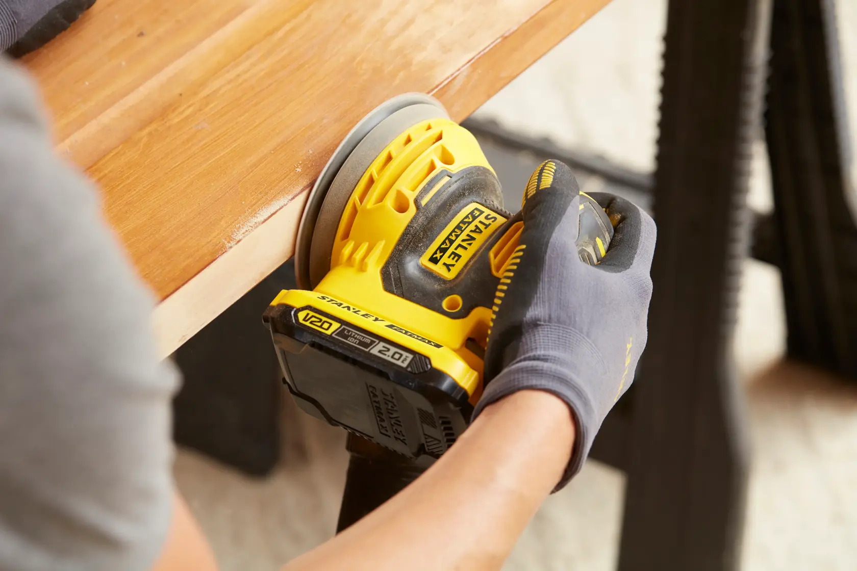 Photo of STANLEY SFMCW220D1S cordless sander being used on wooden surface.