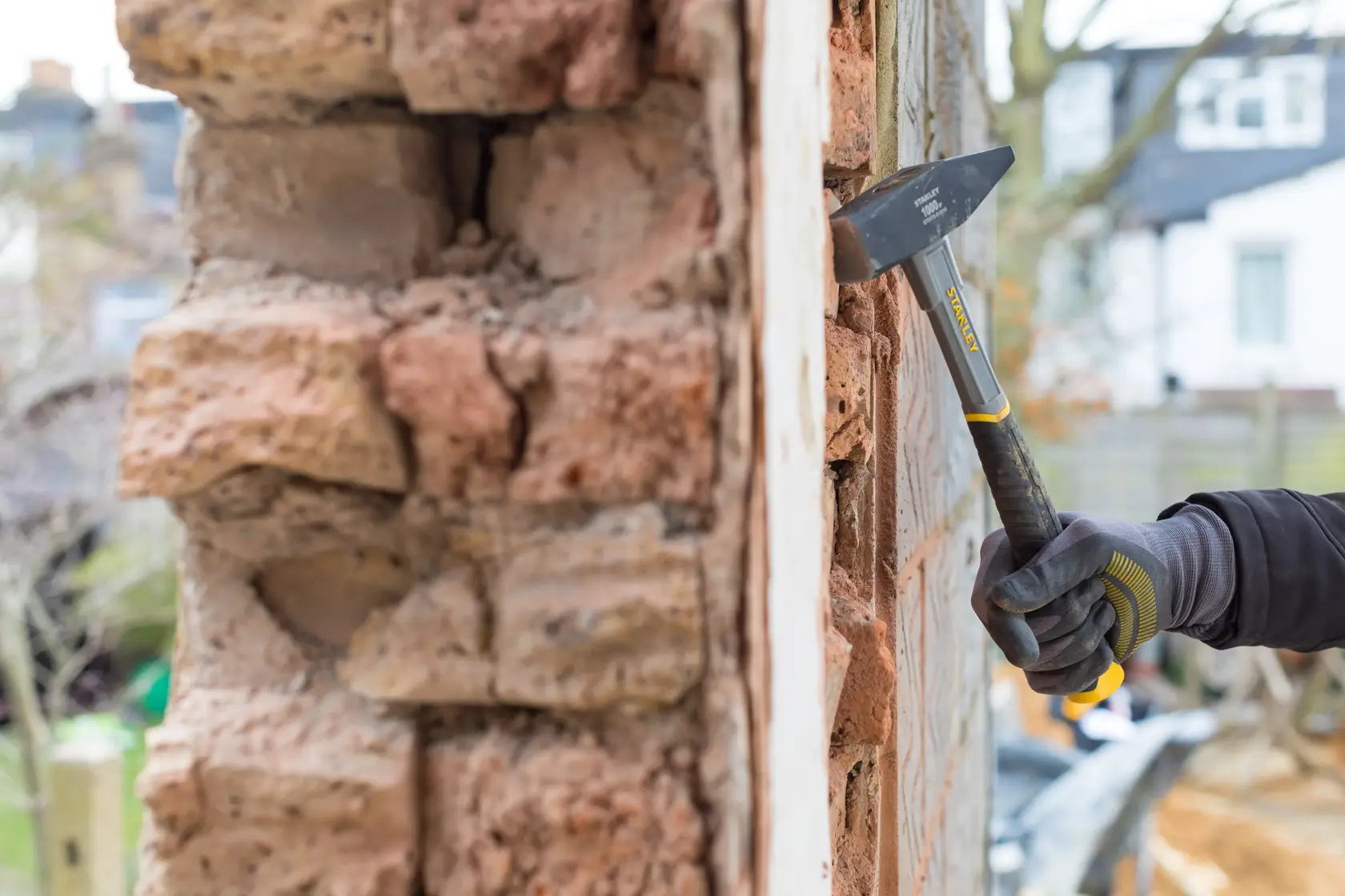 STANLEY STHT0-51910 Ziegelhammer im Einsatz an einer Mauer, Nahaufnahme, Arbeiter mit Handschuhen.