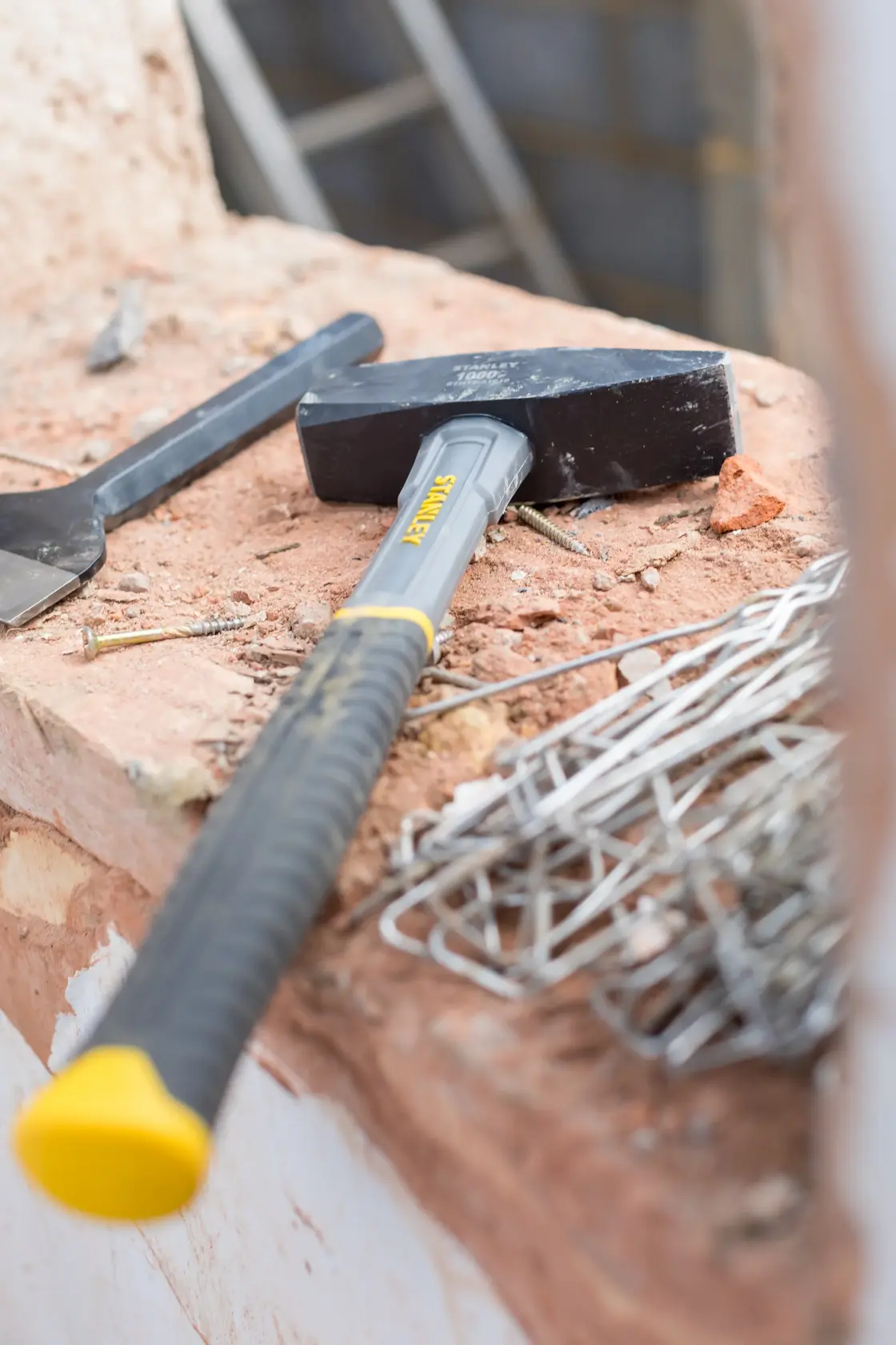 STANLEY STHT0-51910 Vorschlaghammer mit schwarzem Kopf und grau-gelbem Griff auf Baustelle.