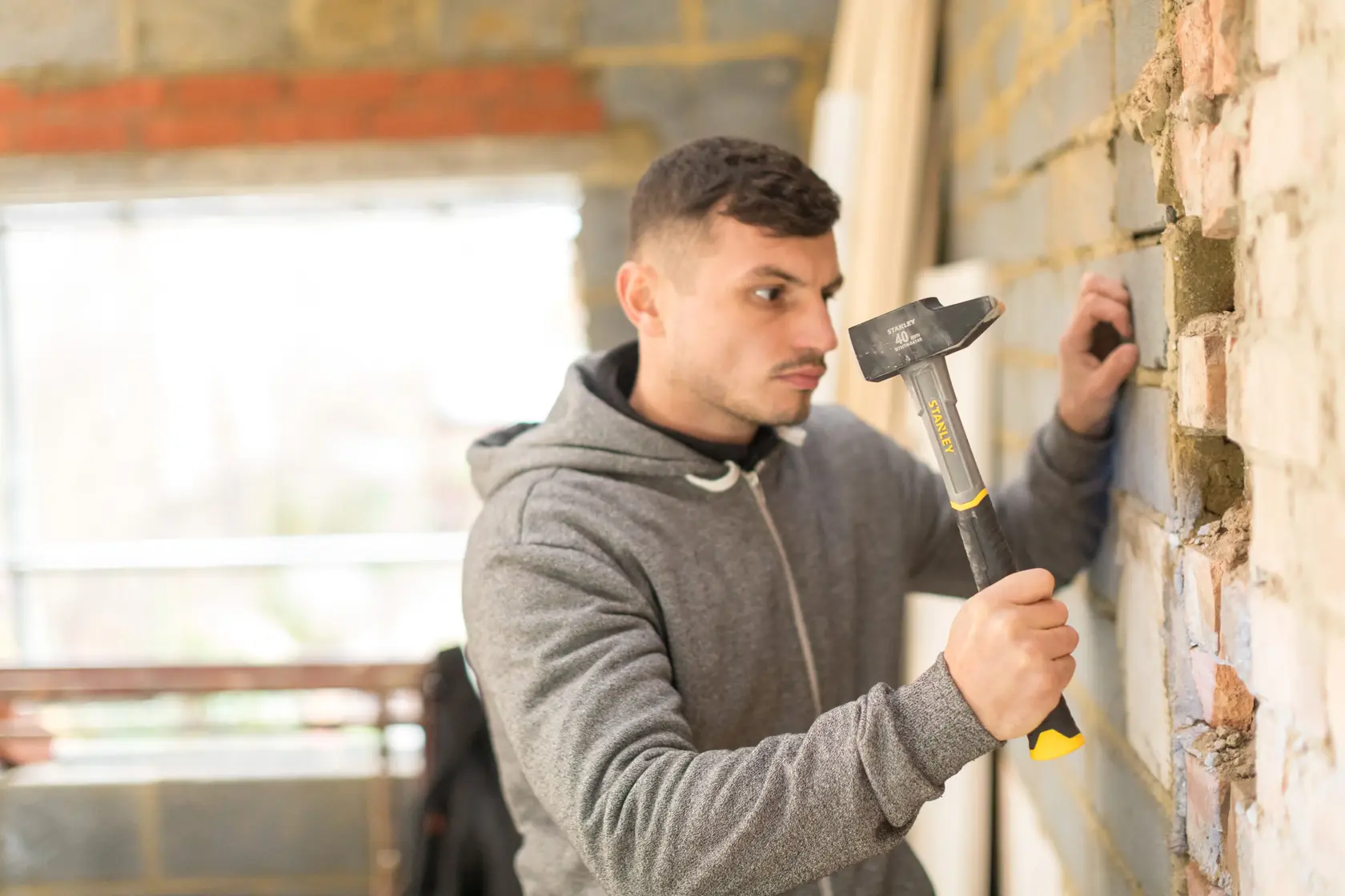 Photo of STANLEY STHT0-54155 hammer in use against a brick wall during construction work.