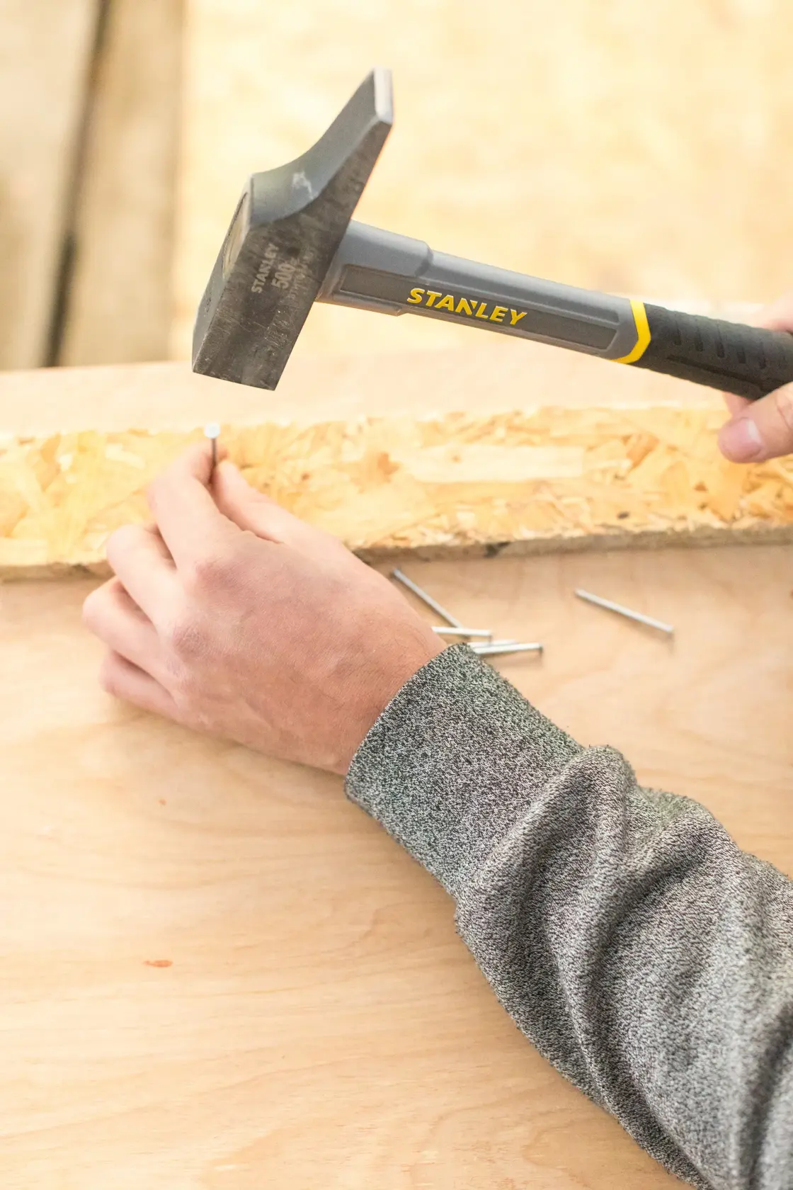 STANLEY STHT0-54160 claw hammer driving nail into wood, close-up photography.