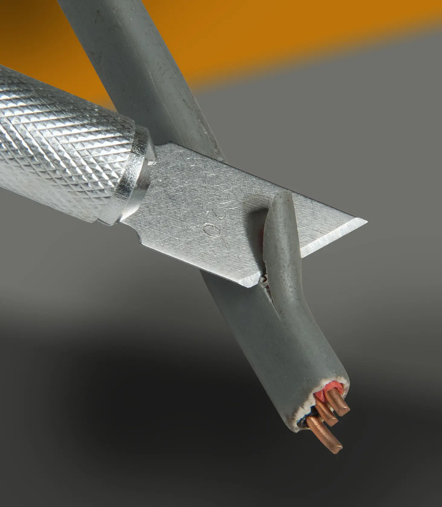 STANLEY STHT0-73872 utility knife cutting gray electrical cable, close-up angle, product photography.