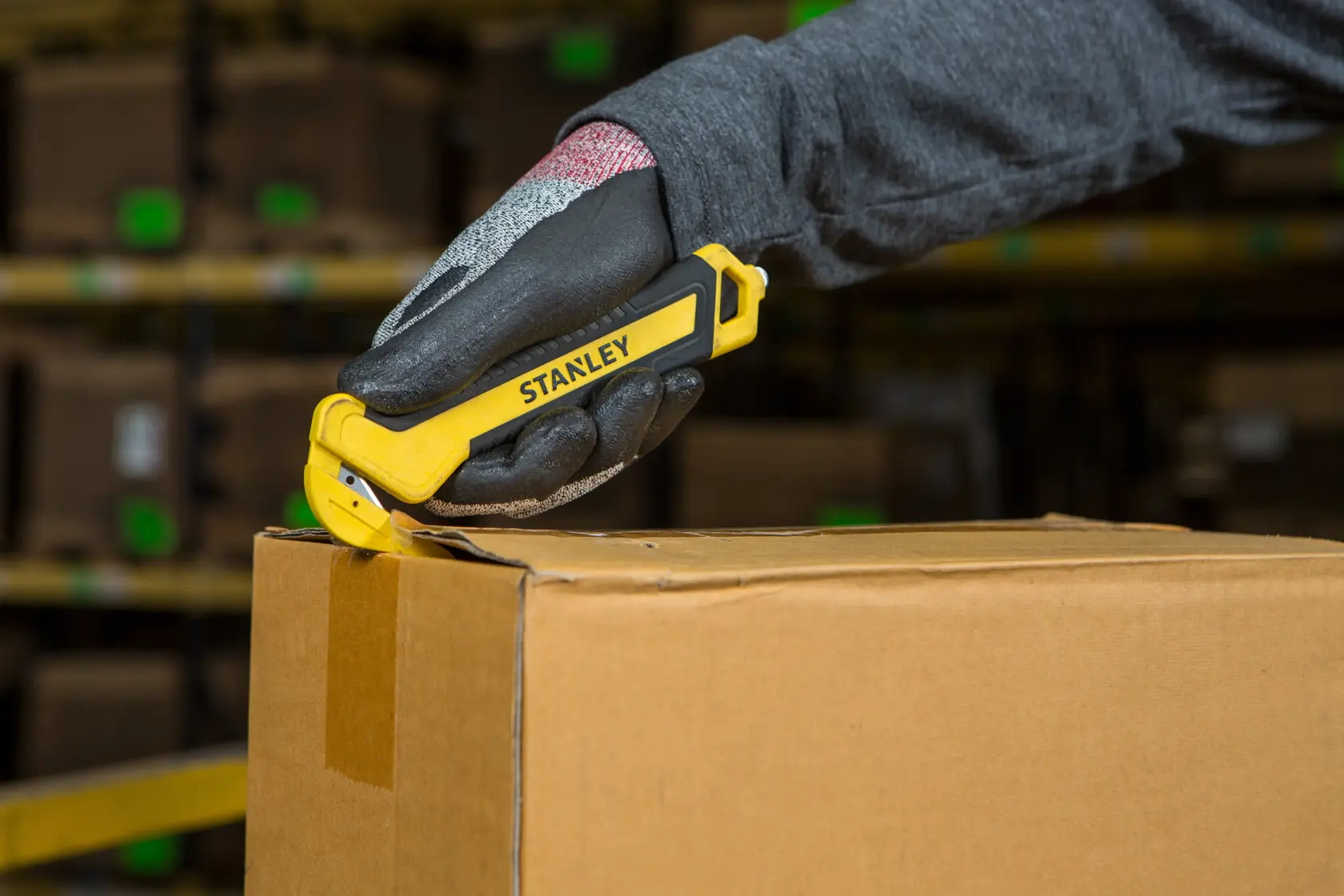STANLEY STHT10356-0 Sicherheitsmesser schneidet Kartonbox, Handgriff, Lagerhintergrund.