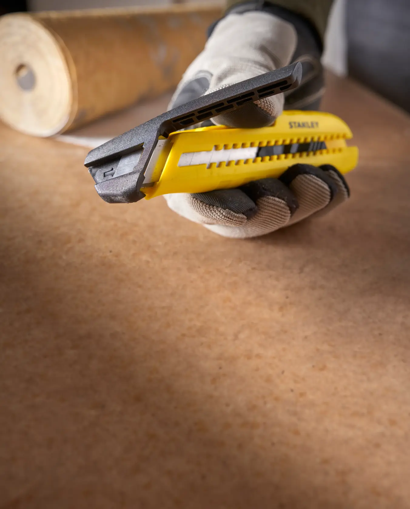 Photo of STANLEY utility knife, SKUs STHT10489, STHT10489-0, yellow handle, close-up in gloved hand, photography category.