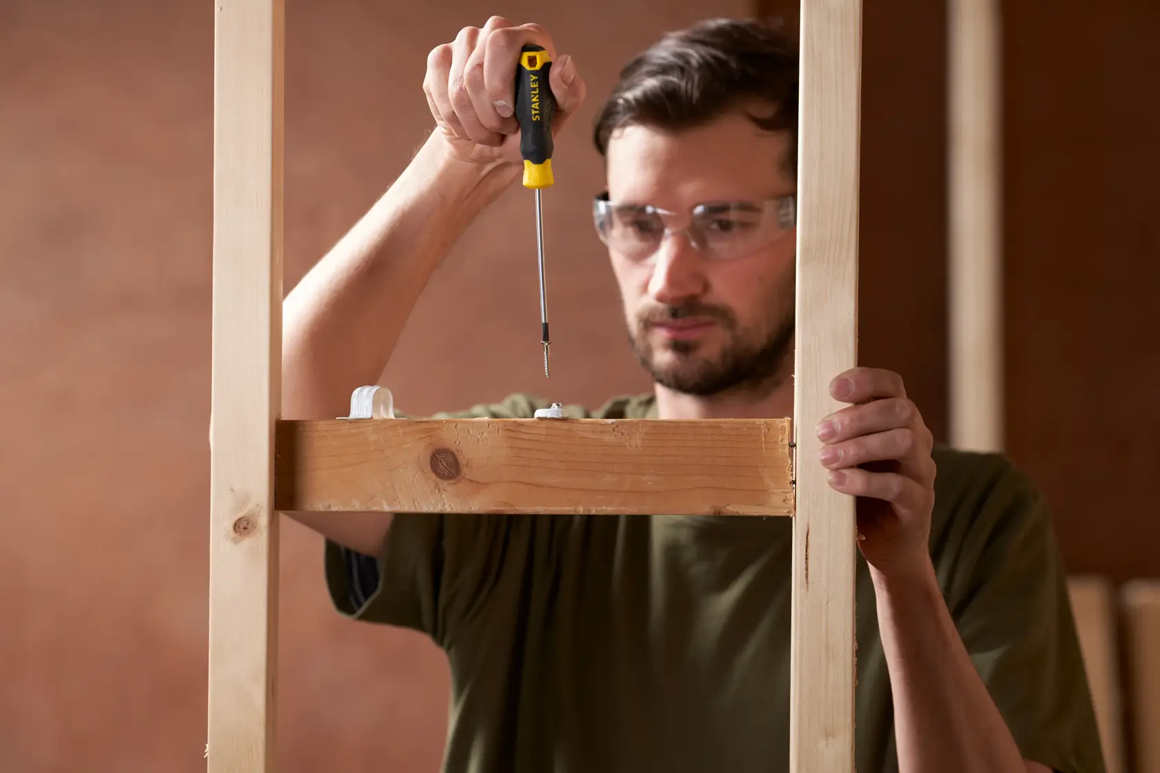 Photo of STANLEY STHT16195-0 screwdriver being used to assemble a wooden frame, close-up view.