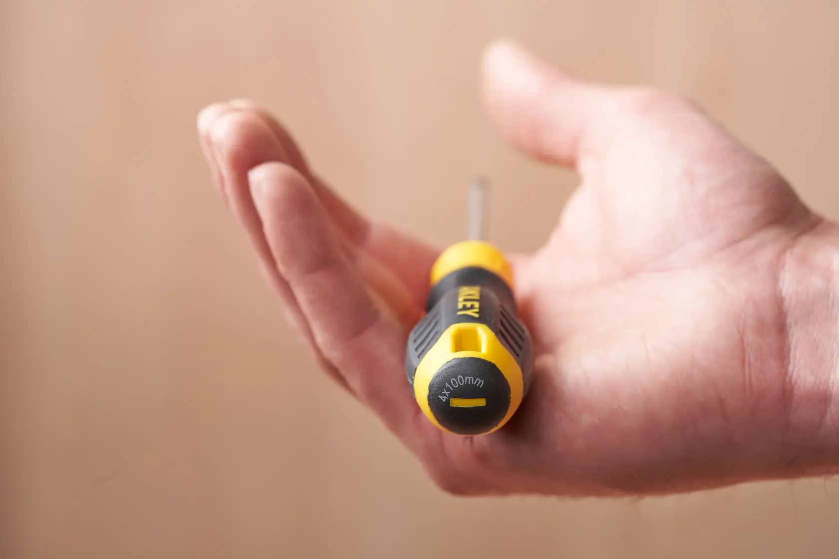 Photo of STANLEY STHT16195-0 screwdriver held in hand, black and yellow handle visible.