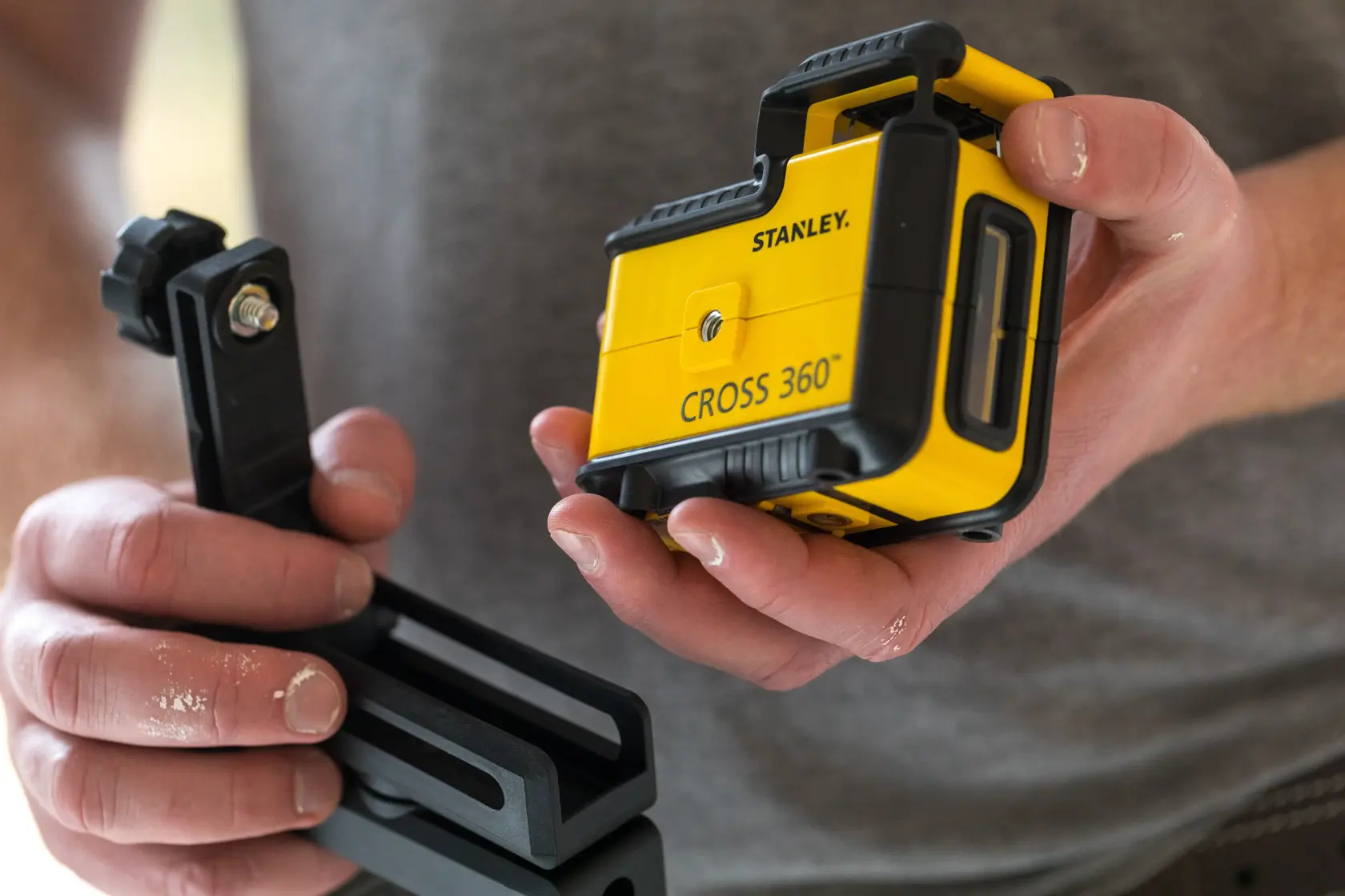Foto des STANLEY STHT77504-1 CROSS 360 Laser-Niveaus mit Montagehalterung, in den Händen gehalten.