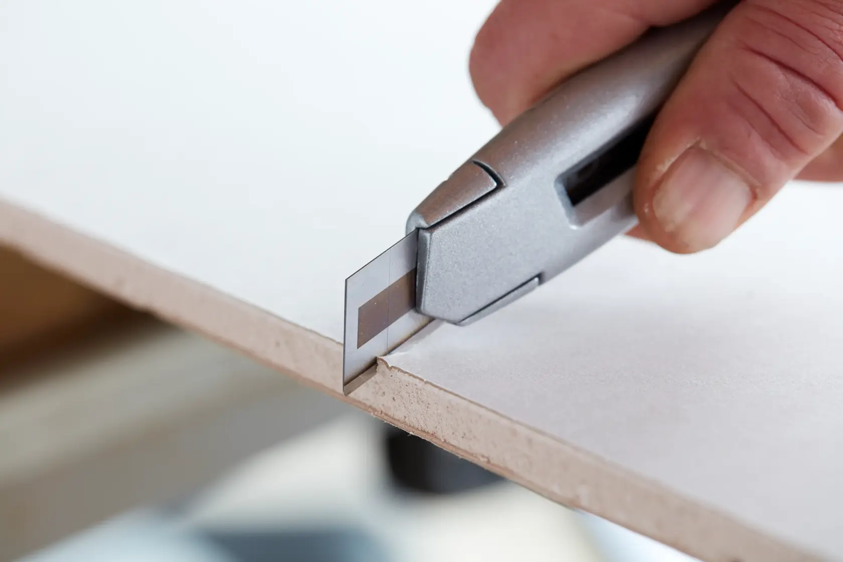 Stanley STHT8-11818 utility knife cutting paperboard, close-up side angle.
