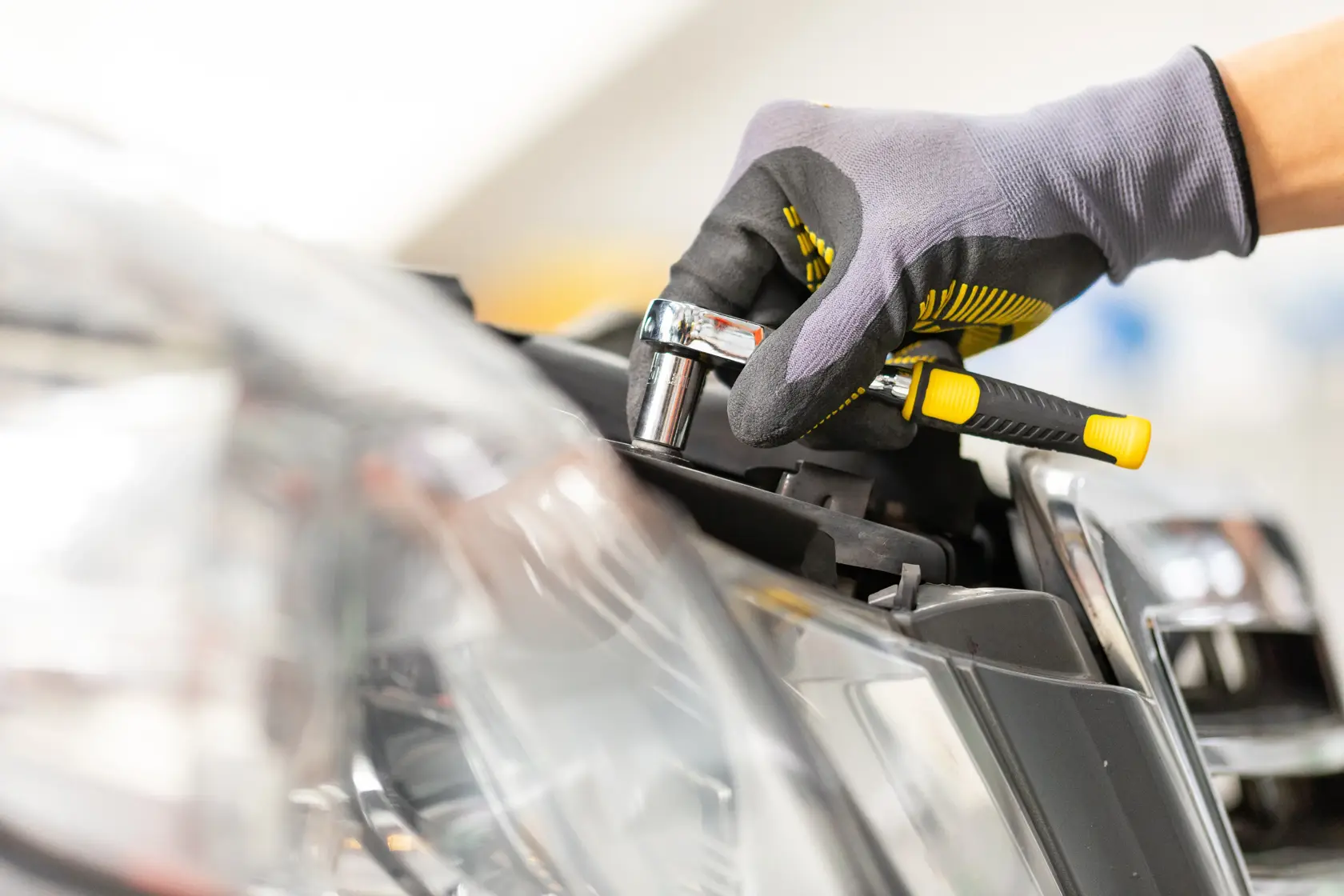 STANLEY STMT82663-0 ratchet used on car headlight, close-up showing grip and tool details.