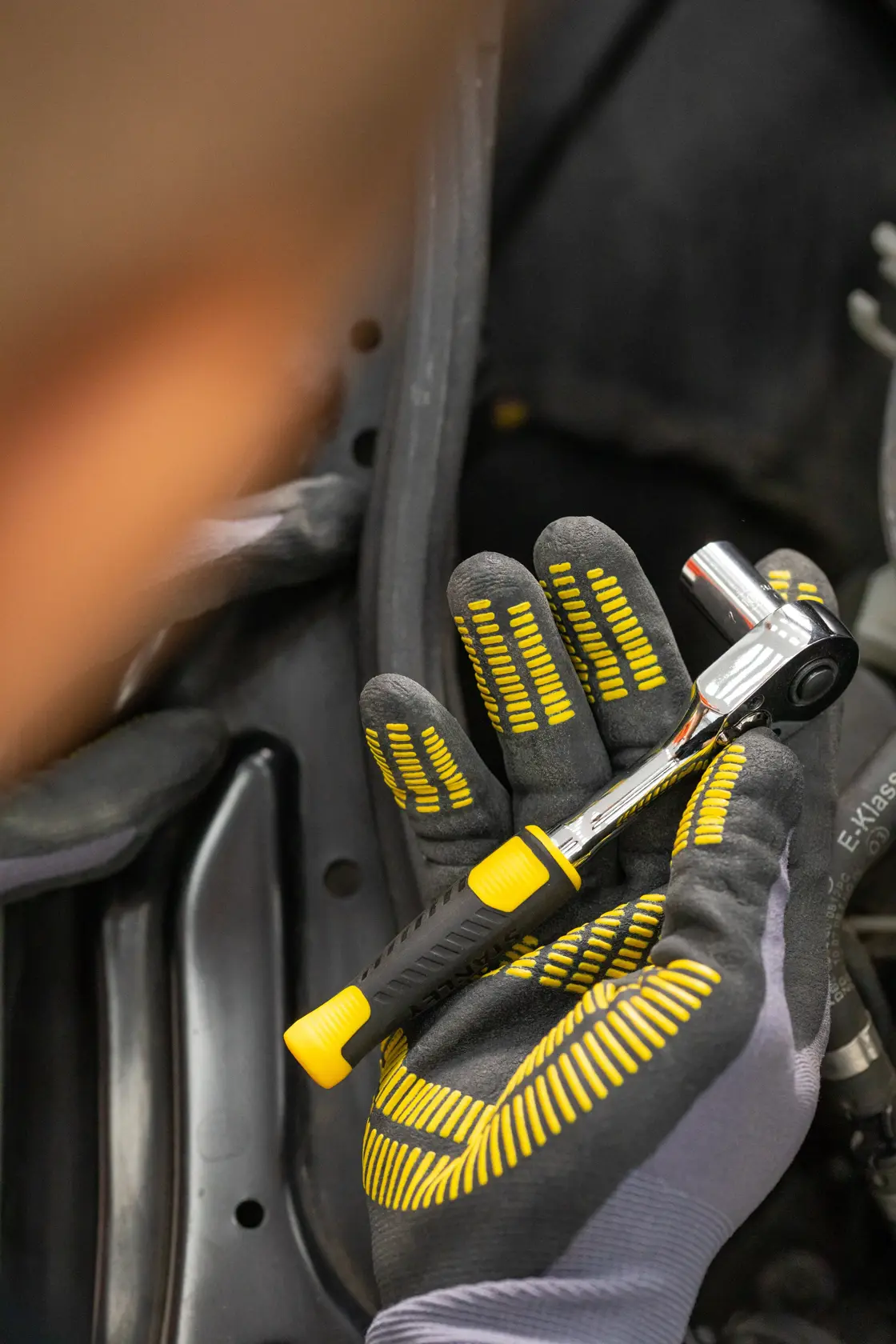 STANLEY STMT82663-0 ratchet wrench with yellow and black handle held in a gloved hand during use.