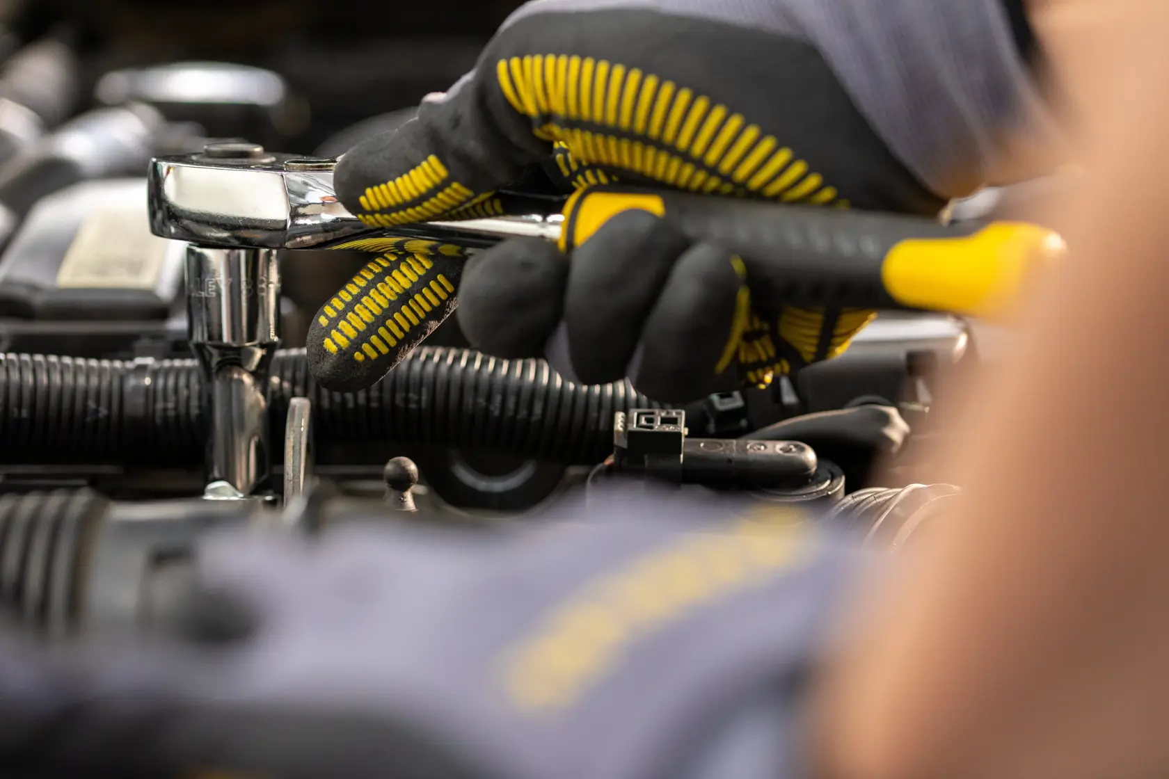 STANLEY STMT82665-0 ratchet wrench in use by a gloved hand on automotive engine, close-up photo.