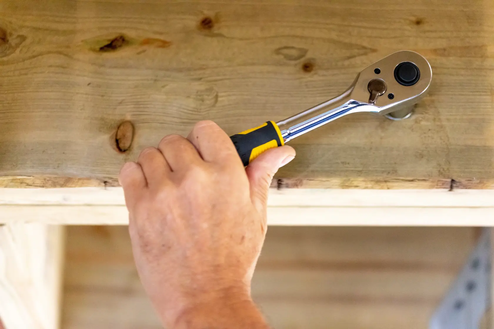 STANLEY STMT82665-0 ratchet hand tool used on wood, close-up of hand holding tool.