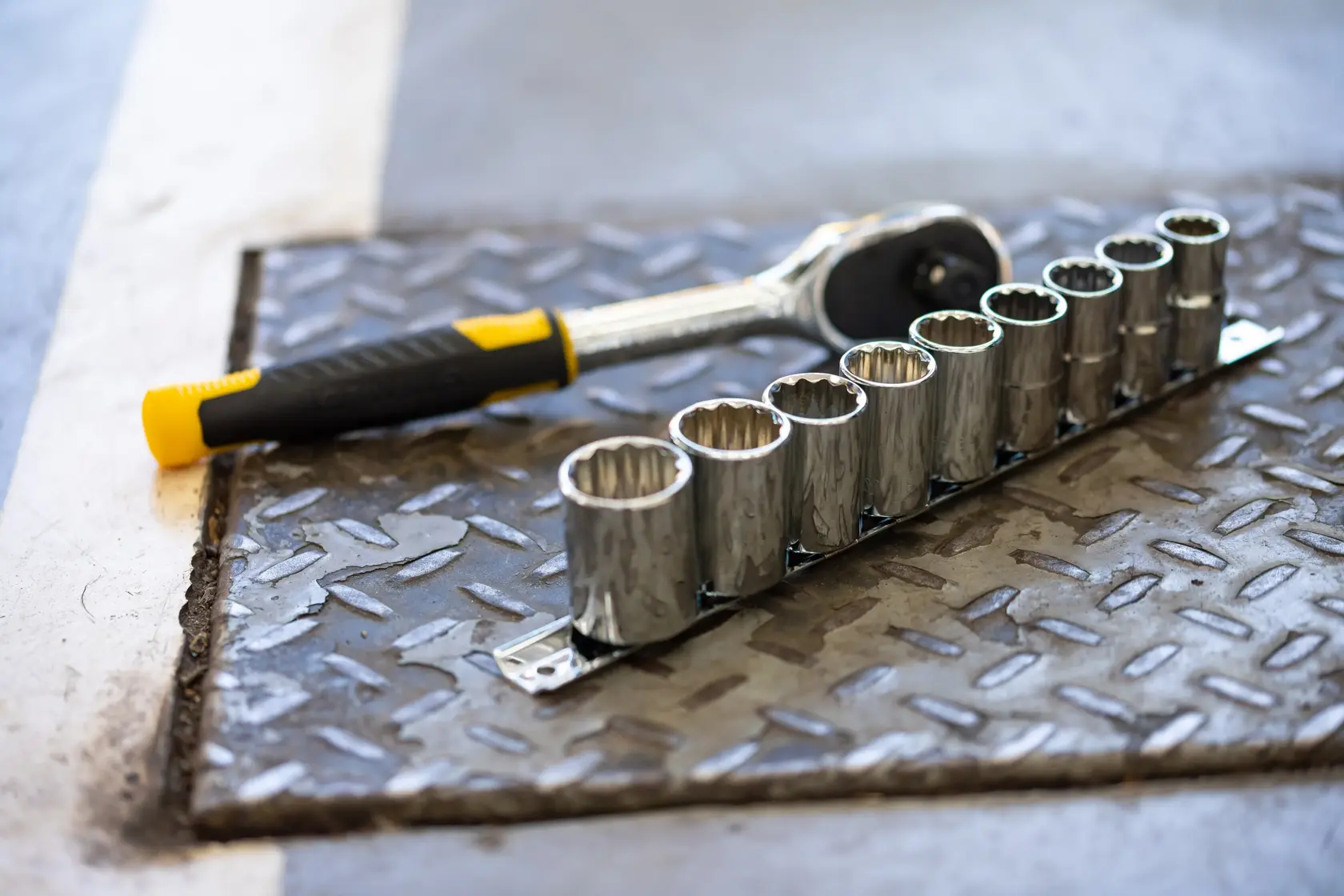 STANLEY STMT82666-0 socket wrench and nine-piece socket set on metal floor, angled view.