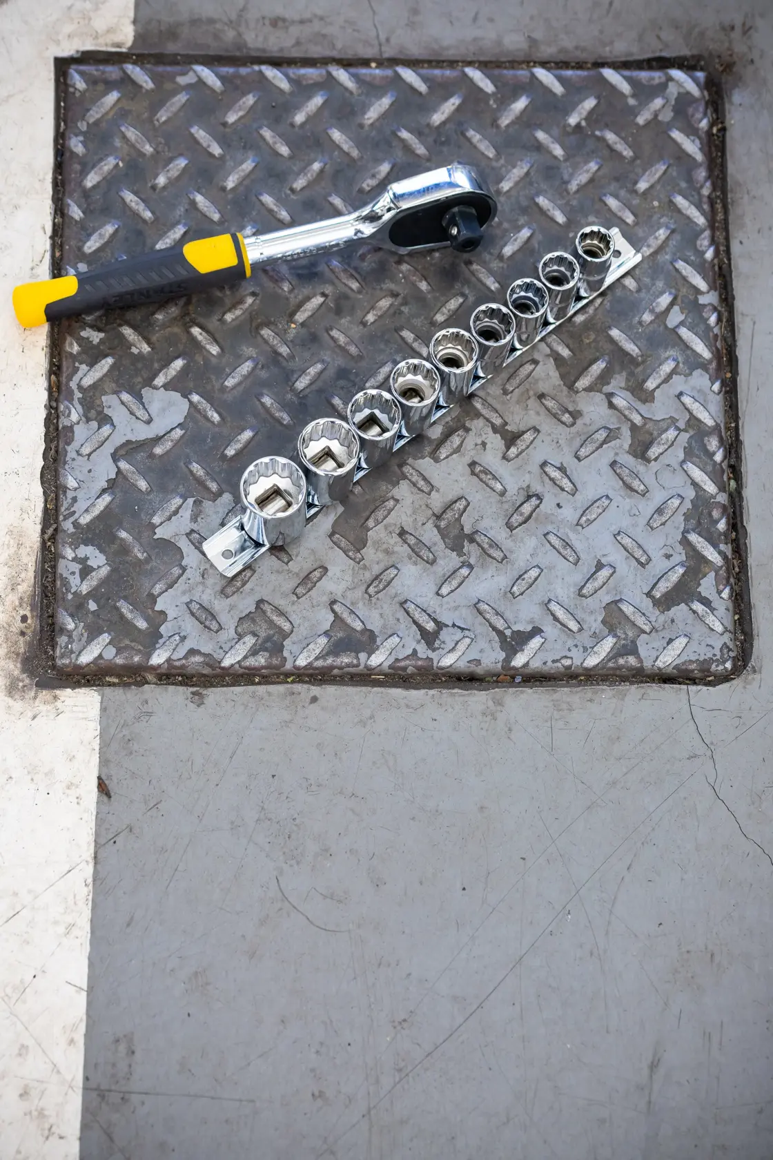 Photo of STANLEY STMT82670-0 ratchet wrench and socket set on metal plate, angled top view.