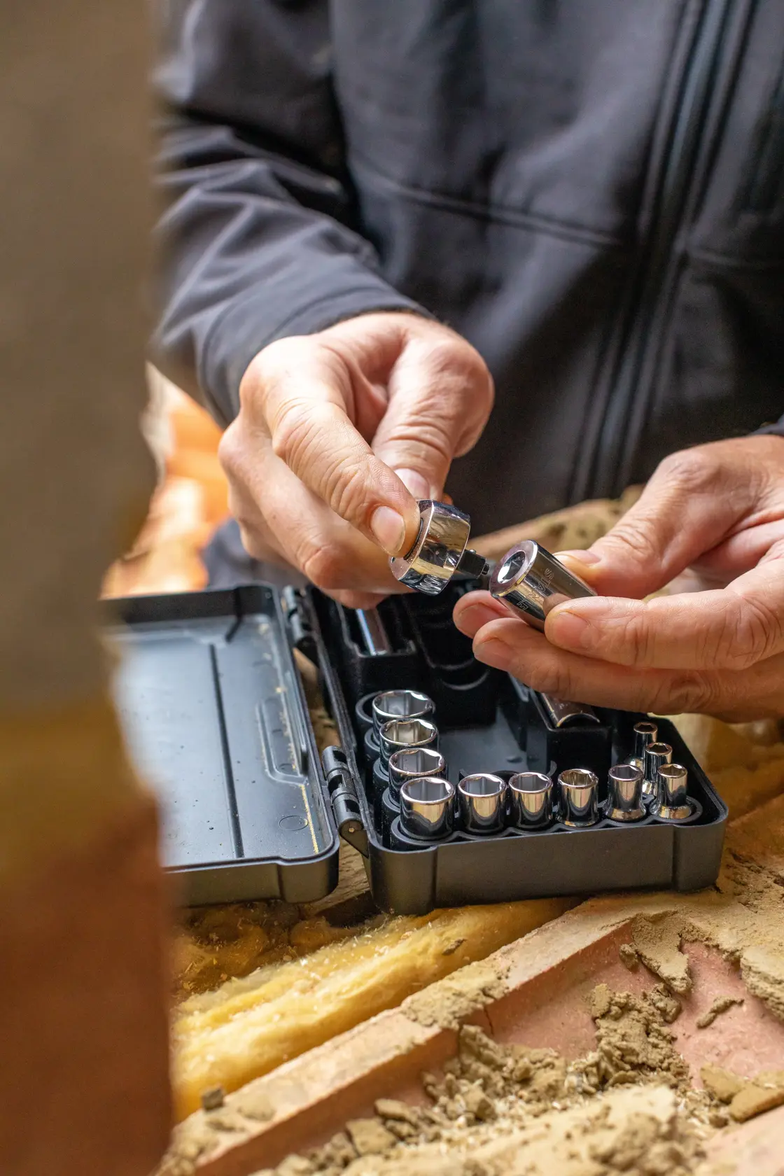 STANLEY STMT82672-0 socket set in black case, hands selecting a socket, close-up on worksite.