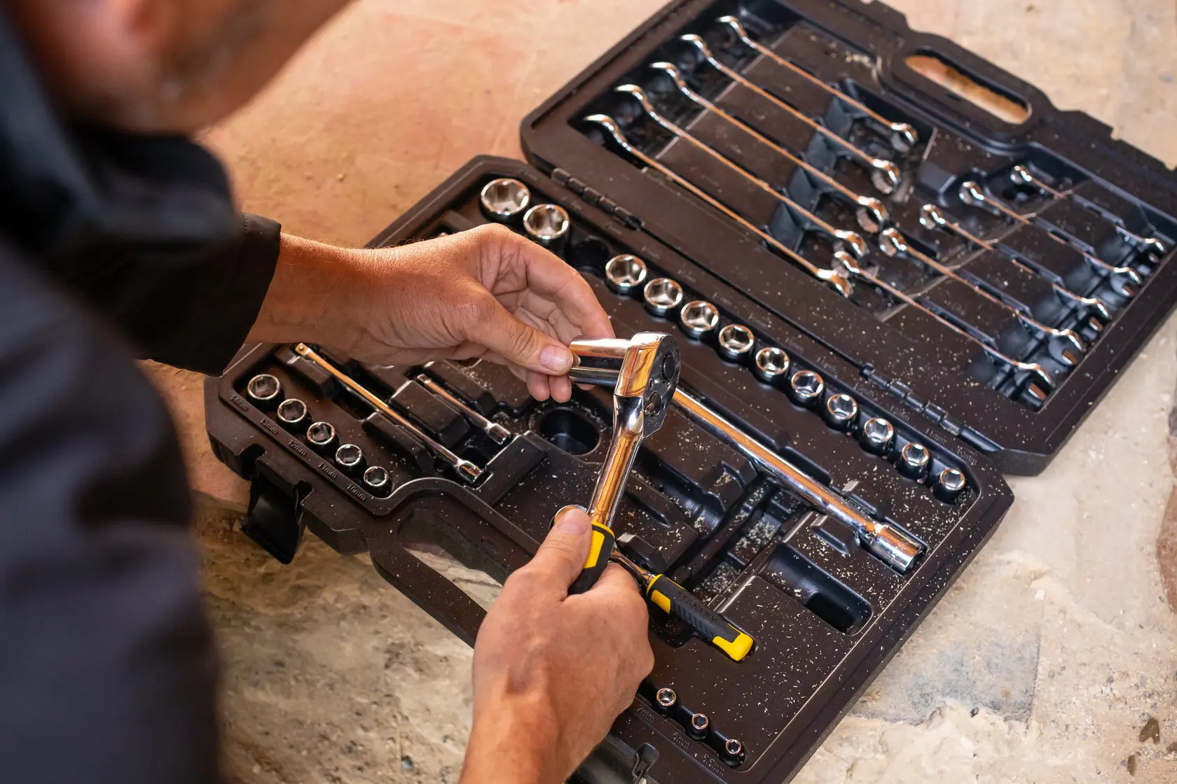 STANLEY STMT82832-1 mechanic tool set with sockets, ratchet, and wrenches in open case, hand holding ratchet.