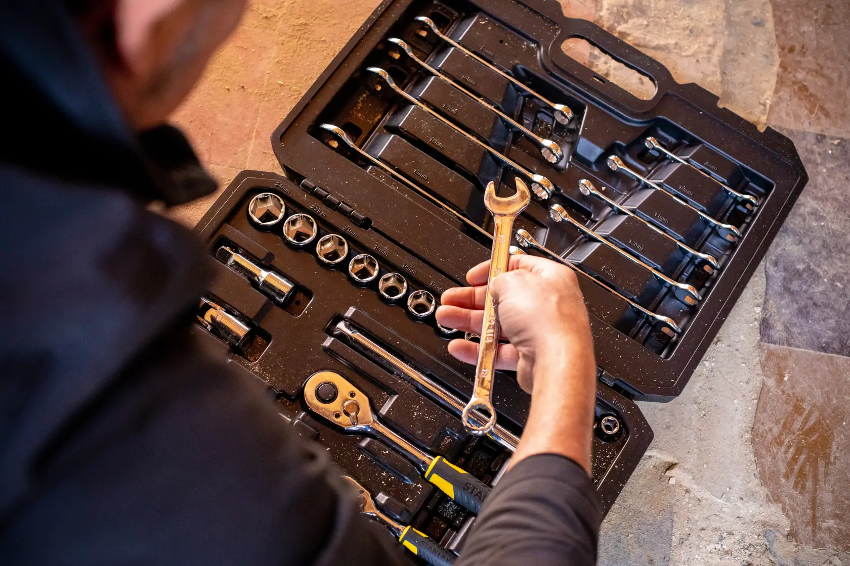 STANLEY STMT82832-1 socket and wrench set in case, person holding wrench, top-down angle.