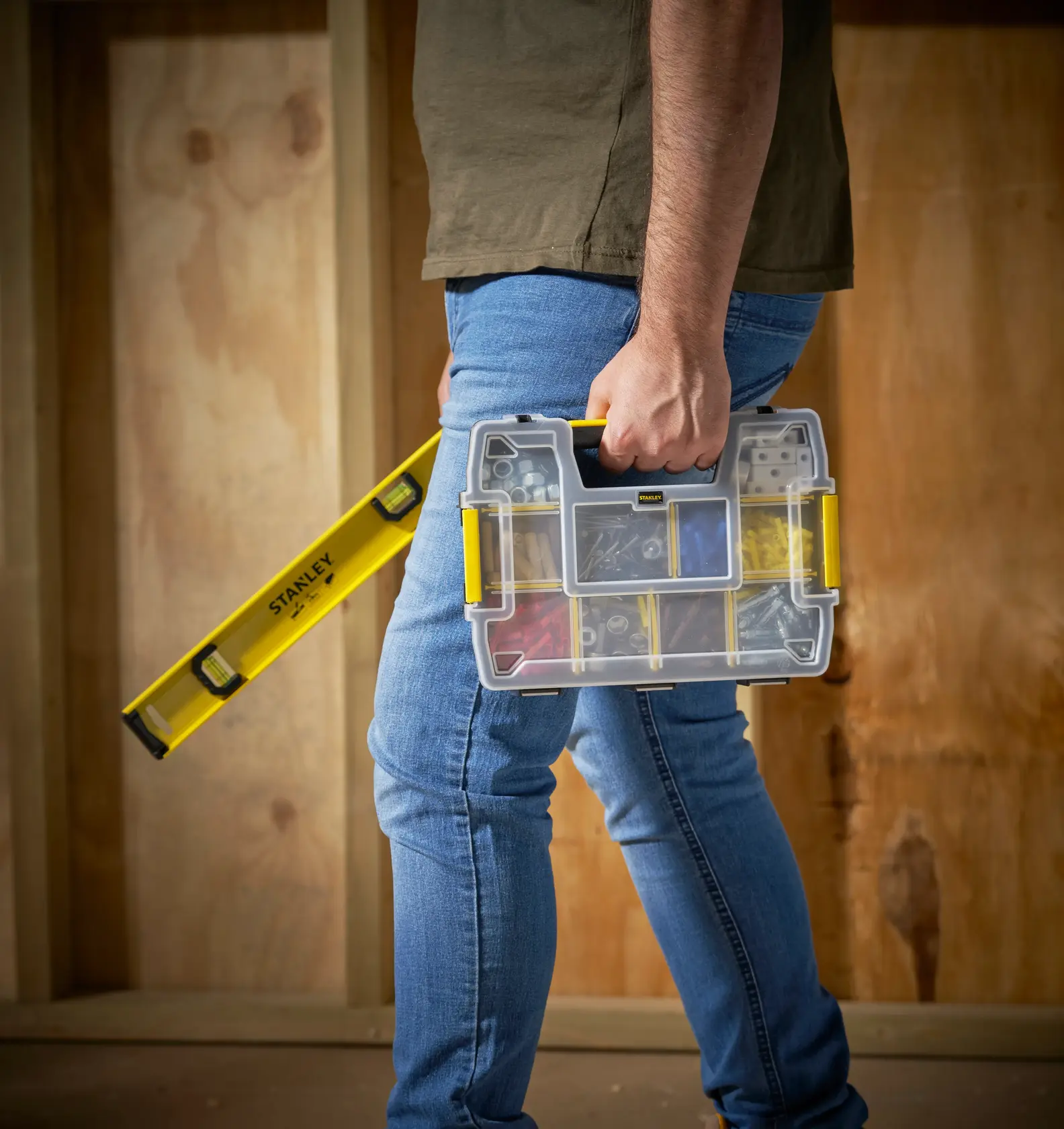 Photo of STANLEY STST1-70720 organizer with clear lid and yellow handle, carried by hand at jobsite.