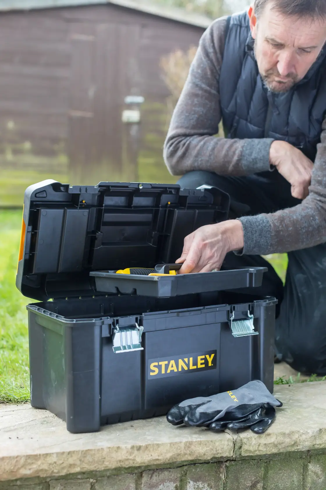 STANLEY toolbox STST1-75521, STST1-75521-KR outdoor use, open lid, gloves beside, man accesses tray.