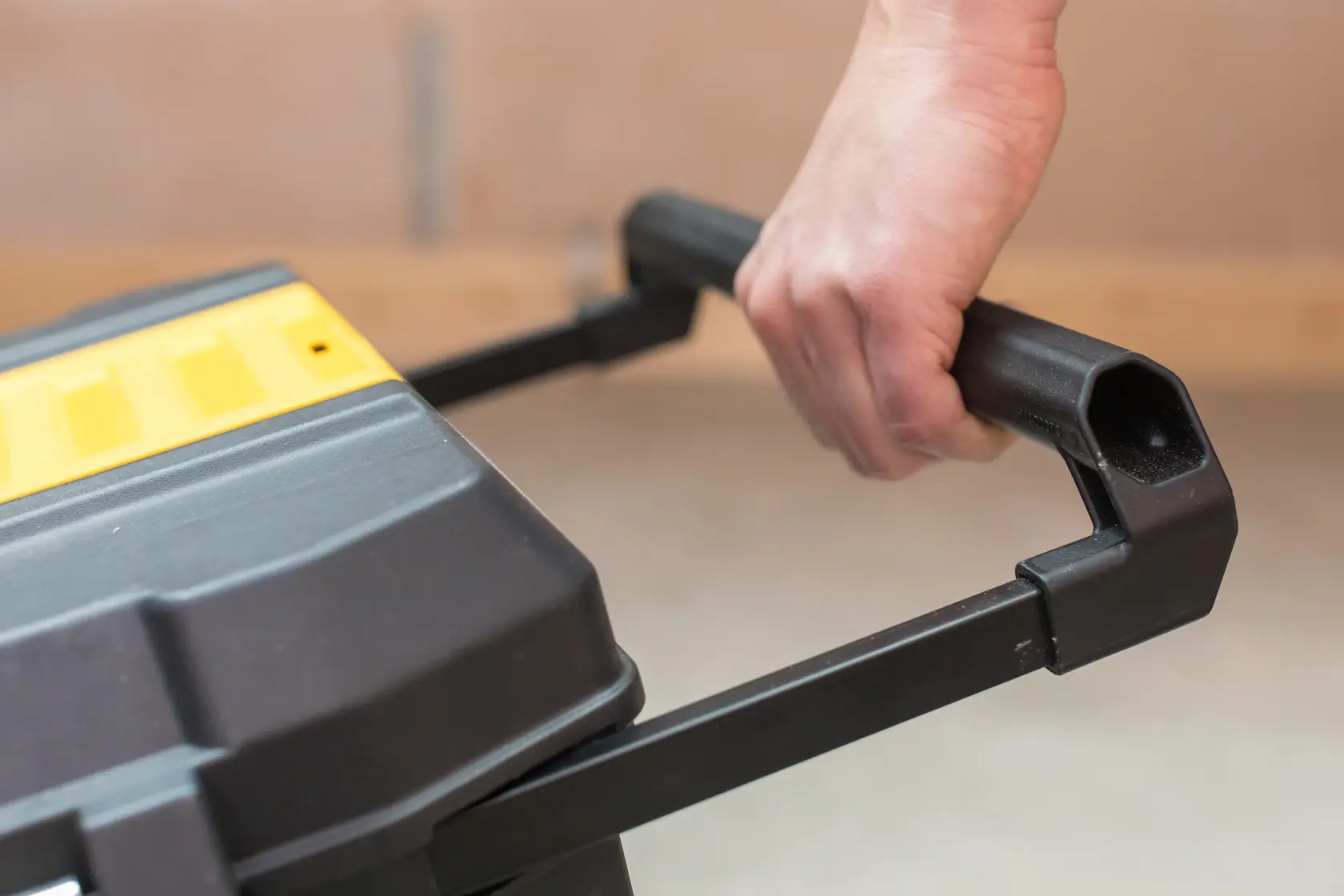 STANLEY STST1-80150 toolbox close-up showing black handle held by hand, partial yellow lid visible.