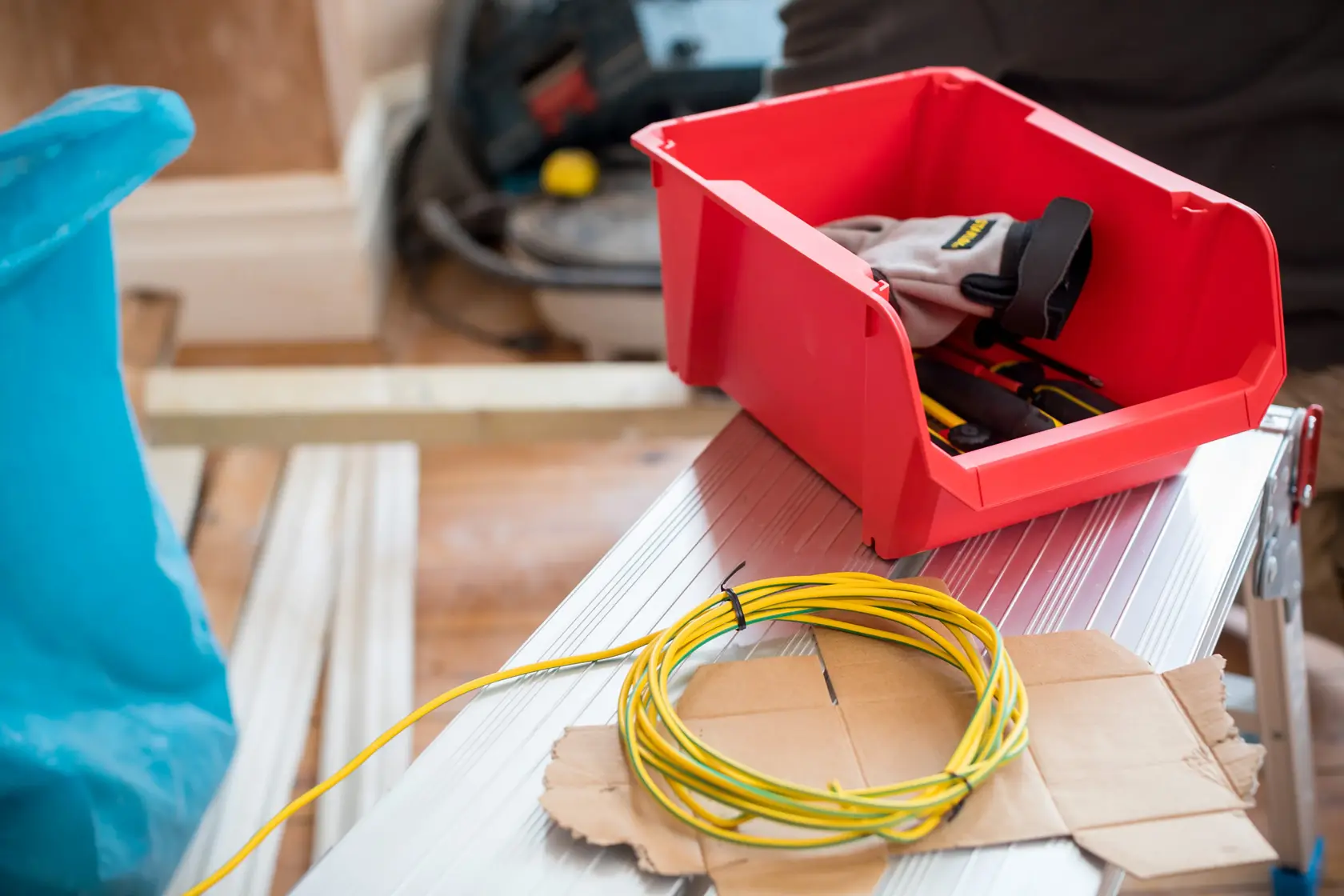 STANLEY STST82742-1 red storage bin with gloves and tools, photographed on a silver workbench with yellow wire.